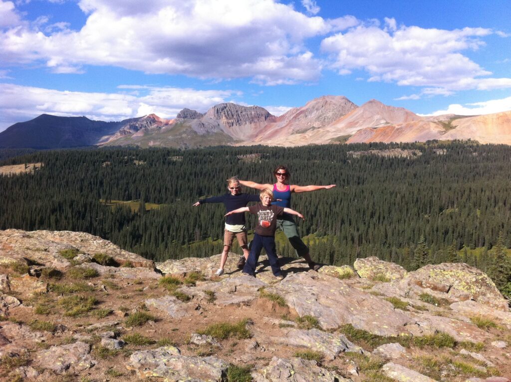 Three people on ridge with mountain view
