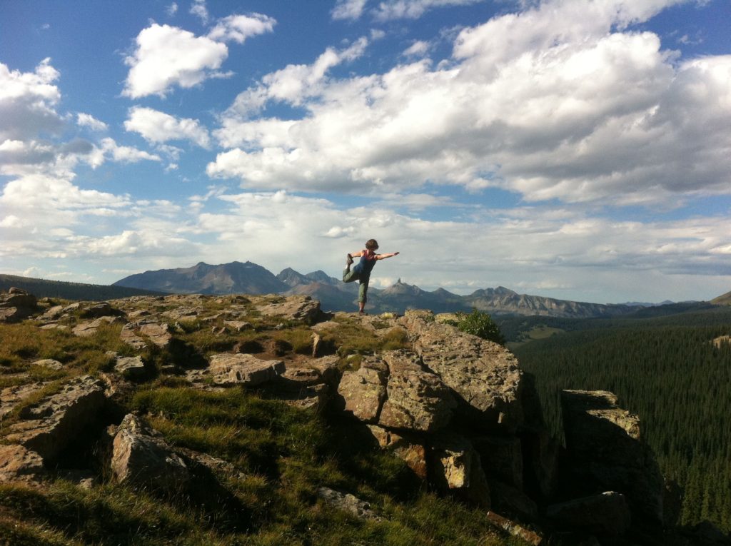 Person balancing on cliff with mountain view