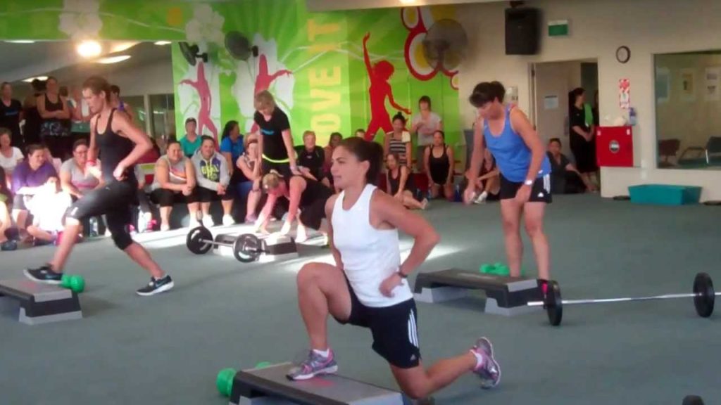 Group fitness class lunges with barbells