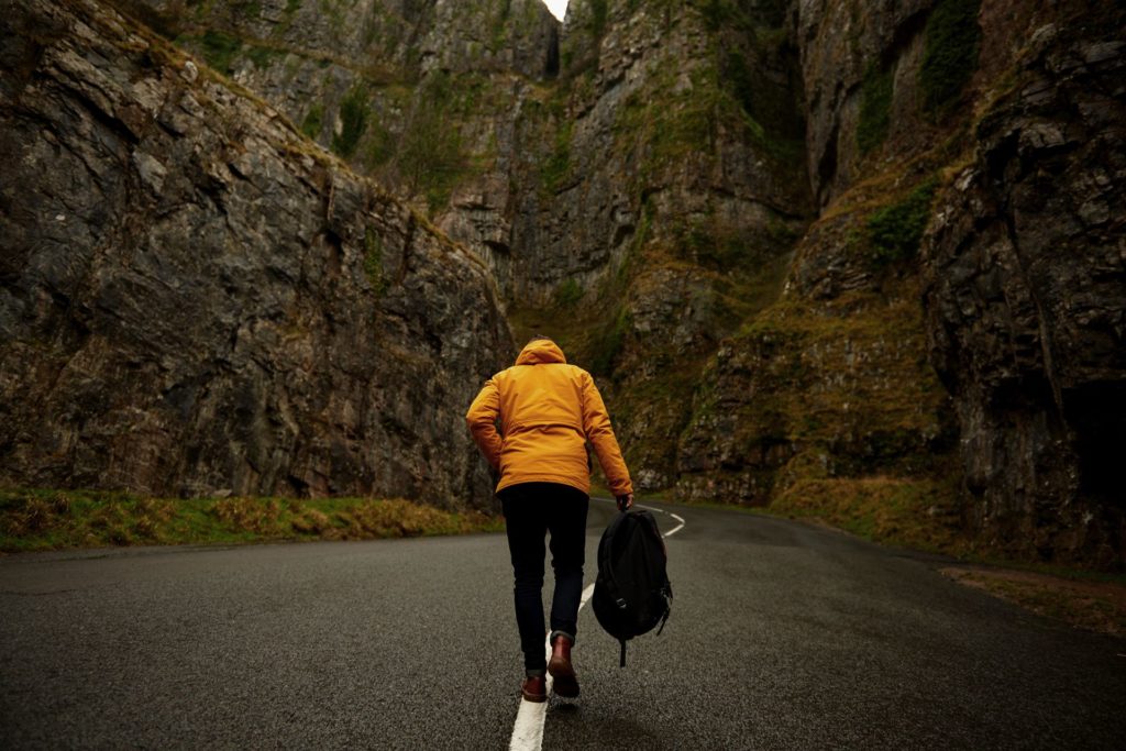 Hiker with backpack walking through rocky canyon