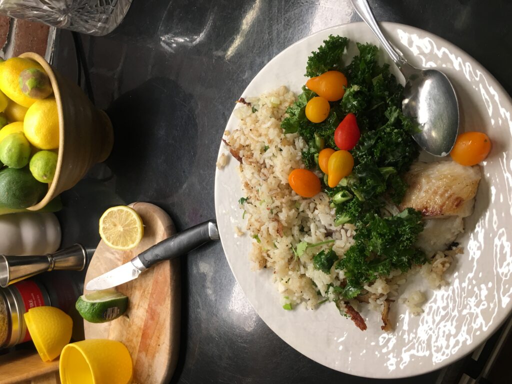 Plate of fish, rice, kale, cherry tomatoes