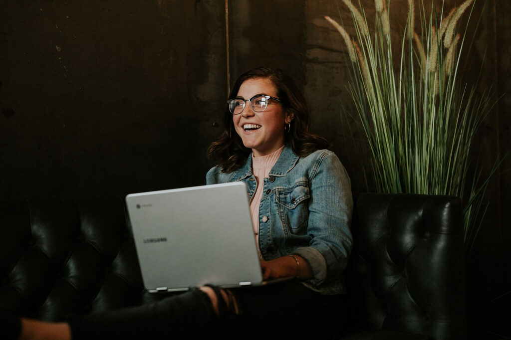 Smiling woman using laptop on leather couch