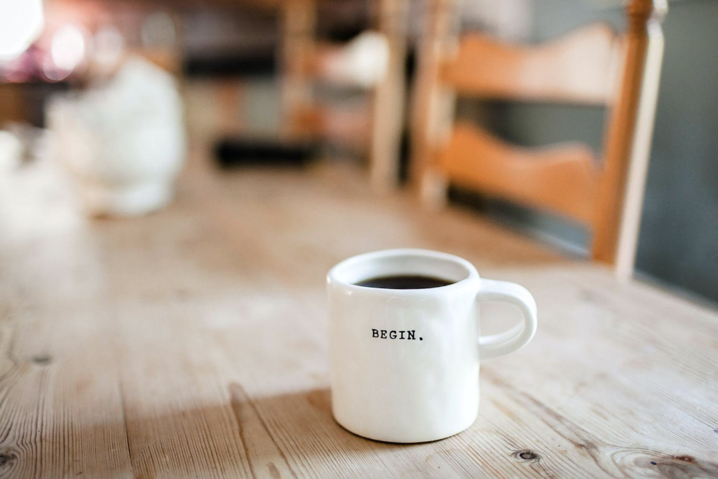 Inspirational Coffee Cup on Wood Table with the word begin on it