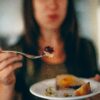 Woman holding up a plate and fork full of food