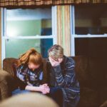 Two people on couch supporting each other through grief, sad and difficult times. Photo Credit Ben White on Unsplash