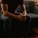 Man sitting on coach with hands clasped on knees