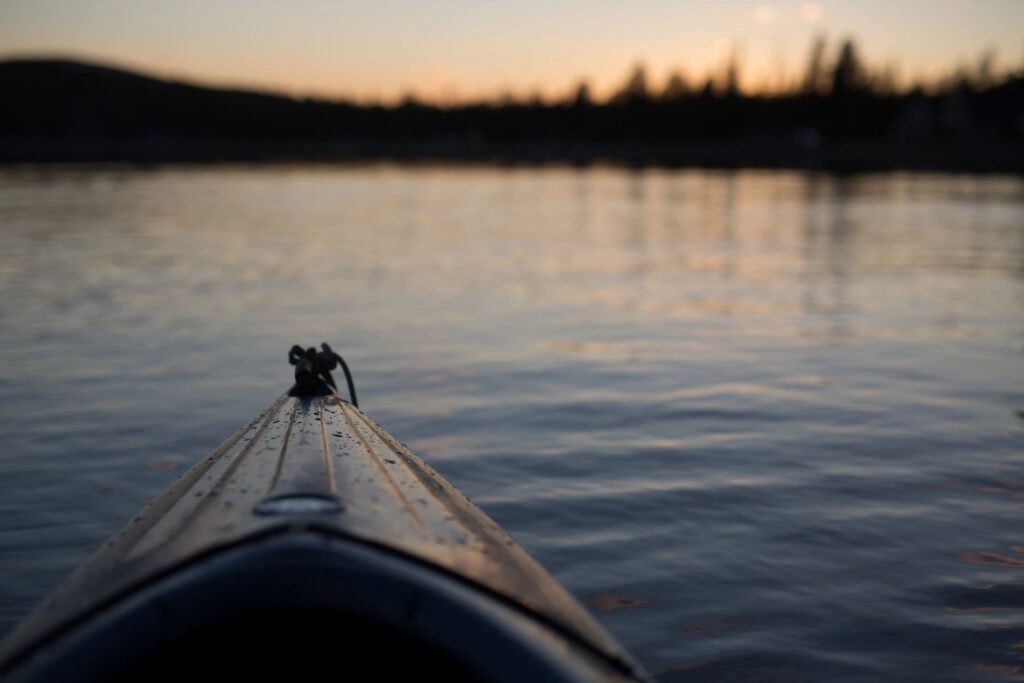 front of kayak paddling in lake at sunrise