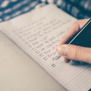 Woman with pen crossing off to do list check boxes