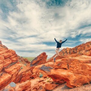 Woman jumping over red rocks