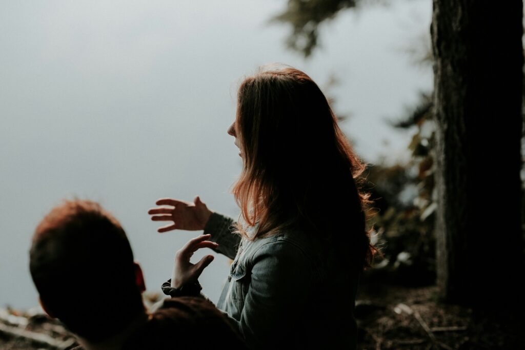 Woman gesturing while talking outdoors near water